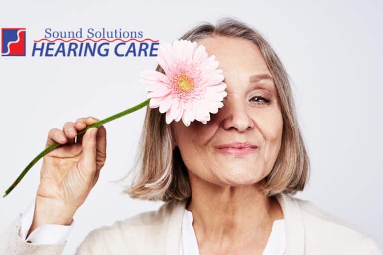 older woman holding a flower in front of her face
